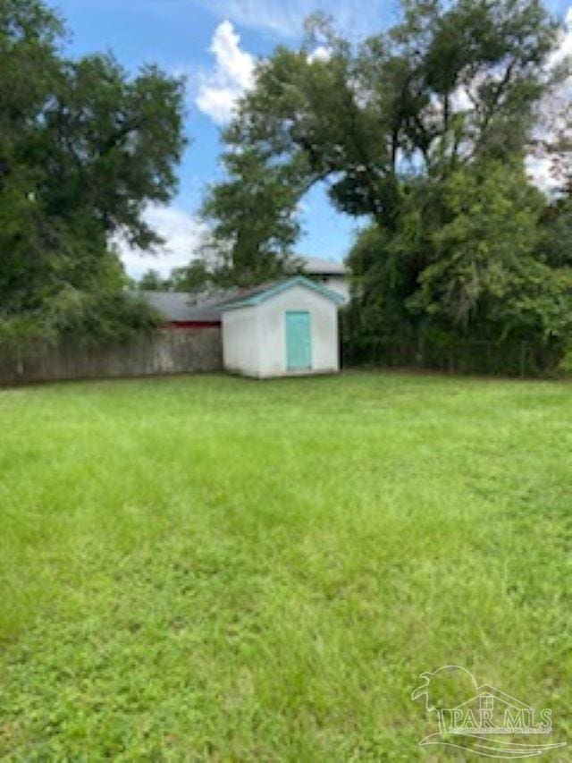 view of yard with fence, an outdoor structure, and a storage unit