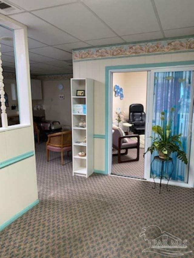interior space with visible vents, baseboards, a drop ceiling, and carpet flooring