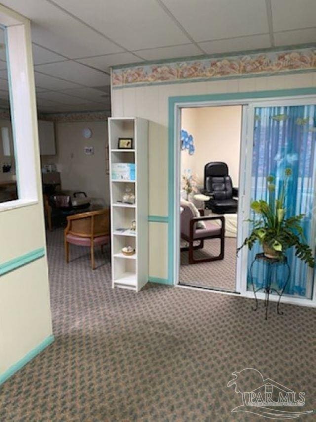 interior space featuring a paneled ceiling, baseboards, and carpet floors