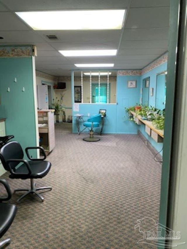 carpeted office with a paneled ceiling