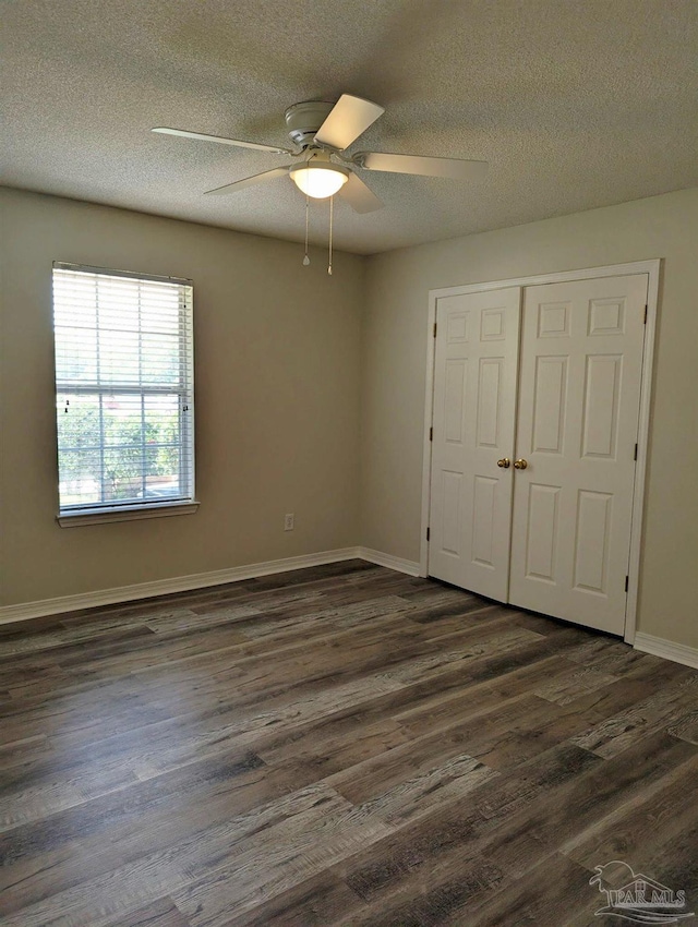 2441 Pine Forest Rd, Pensacola, FL 32533 - unfurnished bedroom featuring dark wood finished floors, a textured ceiling, a closet, a ceiling fan, and baseboards