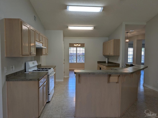 2441 Pine Forest Rd, Pensacola, FL 32533 - kitchen featuring white range with gas cooktop, dark countertops, under cabinet range hood, a kitchen breakfast bar, and a chandelier