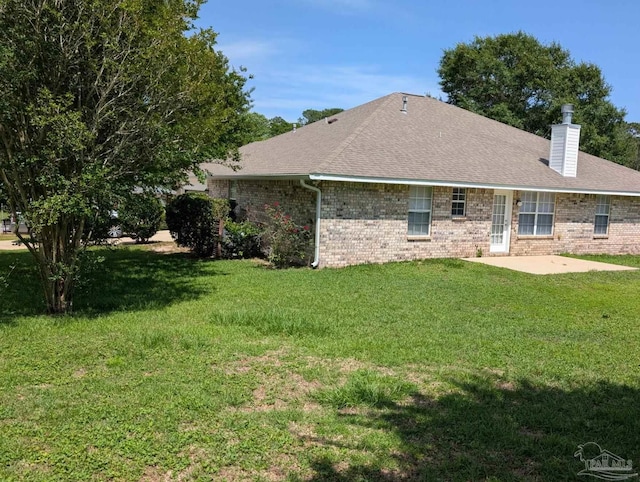2441 Pine Forest Rd, Pensacola, FL 32533 - back of house featuring a patio area, a chimney, brick siding, a yard, and a shingled roof