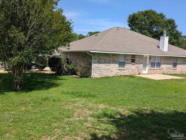 2441 Pine Forest Rd, Pensacola, FL 32533 - back of house featuring a patio area, a chimney, brick siding, a yard, and a shingled roof