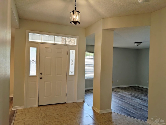 2441 Pine Forest Rd, Pensacola, FL 32533 - tiled entryway featuring baseboards, a textured ceiling, and a chandelier