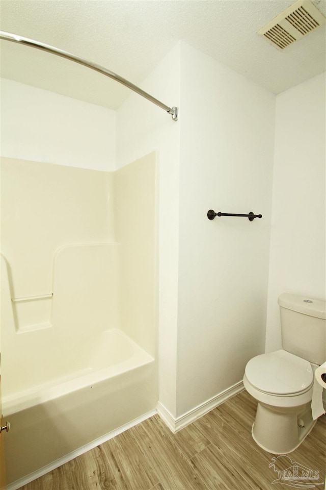 bathroom featuring shower / bathing tub combination, toilet, and wood-type flooring