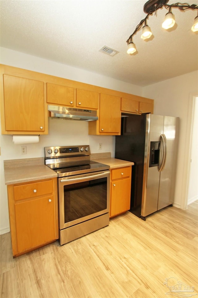 kitchen with appliances with stainless steel finishes and light hardwood / wood-style floors