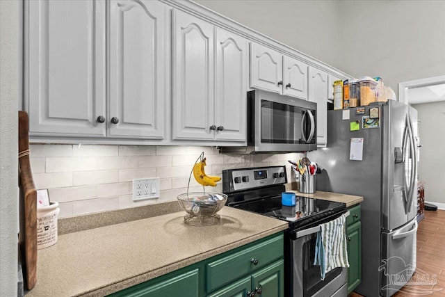 2863 Wallace Lake Rd, Pace, FL 32571 - kitchen featuring stainless steel appliances, white cabinetry, wood finished floors, tasteful backsplash, and green cabinets