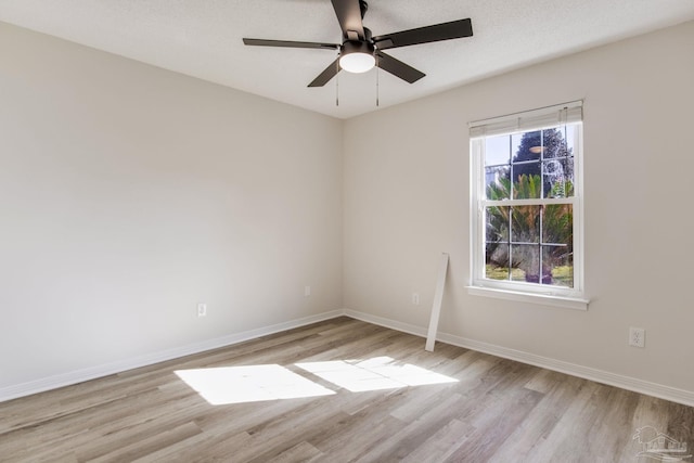 spare room with light wood-style floors, ceiling fan, and baseboards