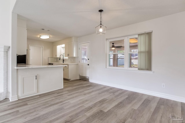 kitchen featuring light wood finished floors, visible vents, light countertops, white cabinets, and baseboards