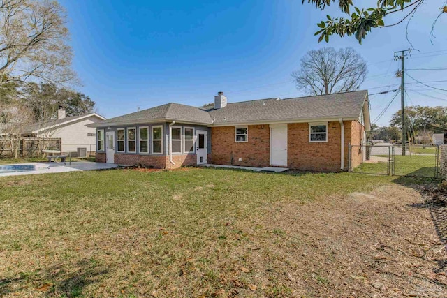 back of house featuring brick siding, a chimney, a lawn, a gate, and fence