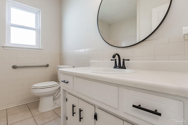 bathroom featuring tile patterned flooring, toilet, a wainscoted wall, vanity, and tile walls