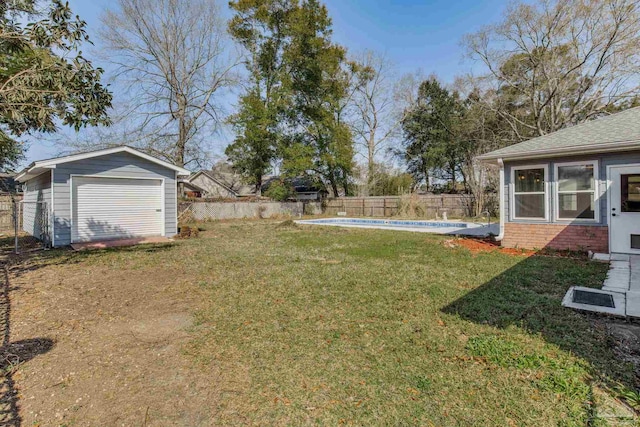 view of yard featuring a garage, an outdoor structure, fence, and a fenced in pool