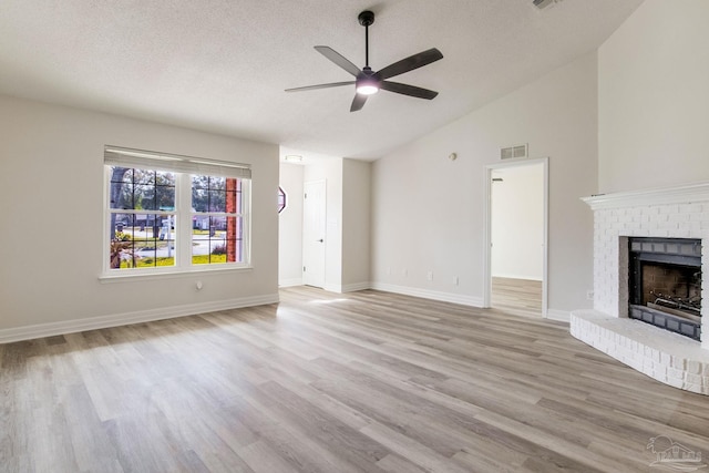 unfurnished living room featuring light wood finished floors, visible vents, a brick fireplace, a textured ceiling, and baseboards