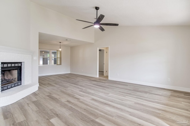 unfurnished living room featuring a brick fireplace, ceiling fan, baseboards, and light wood-style floors