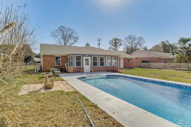 back of house with a fenced in pool, brick siding, a chimney, a lawn, and fence