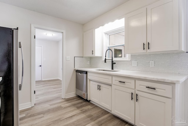 kitchen featuring light wood-style flooring, refrigerator, a sink, decorative backsplash, and dishwasher