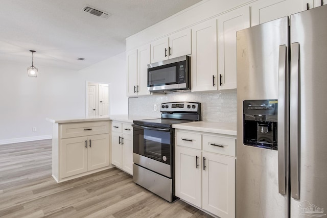 kitchen featuring stainless steel appliances, a peninsula, visible vents, light wood finished floors, and tasteful backsplash