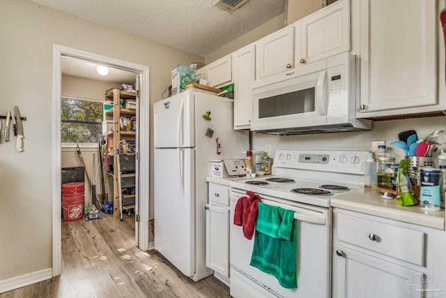 kitchen with light wood-type flooring, a textured ceiling, white appliances, and white cabinetry