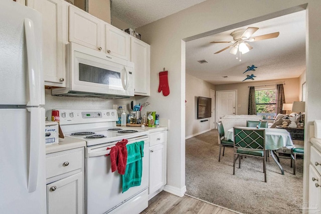 kitchen featuring white appliances, white cabinets, light hardwood / wood-style flooring, ceiling fan, and a textured ceiling