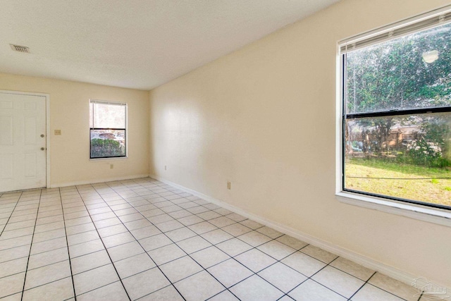 tiled empty room featuring a textured ceiling