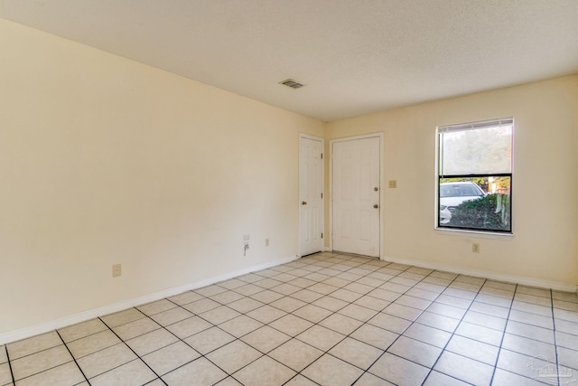 empty room with a textured ceiling and light tile patterned flooring