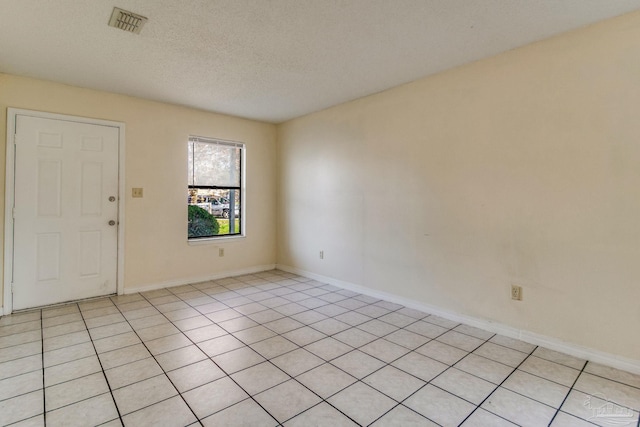 tiled spare room with a textured ceiling