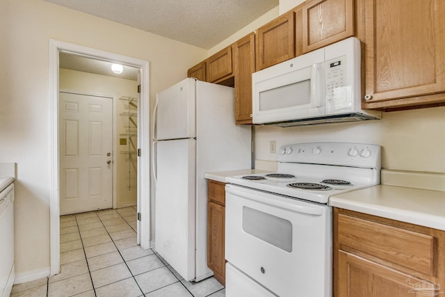 kitchen with white appliances, a textured ceiling, and light tile patterned floors