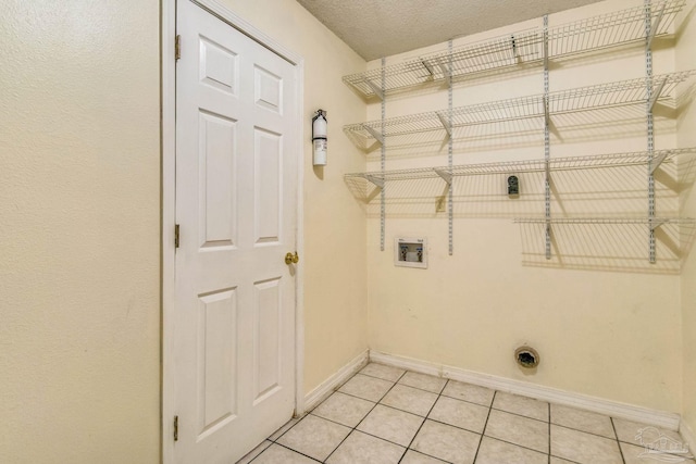 clothes washing area with washer hookup, electric dryer hookup, light tile patterned floors, and a textured ceiling