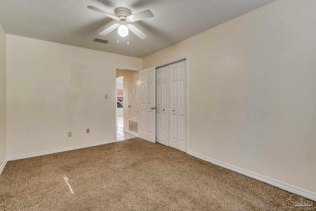 unfurnished bedroom featuring carpet flooring, ceiling fan, and a textured ceiling