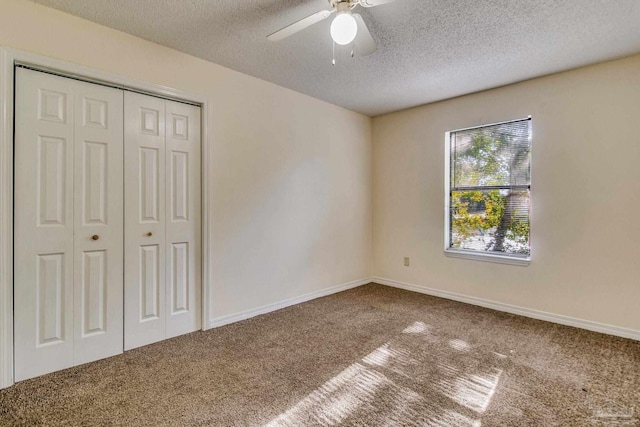 unfurnished bedroom with a textured ceiling, carpet floors, a closet, and ceiling fan