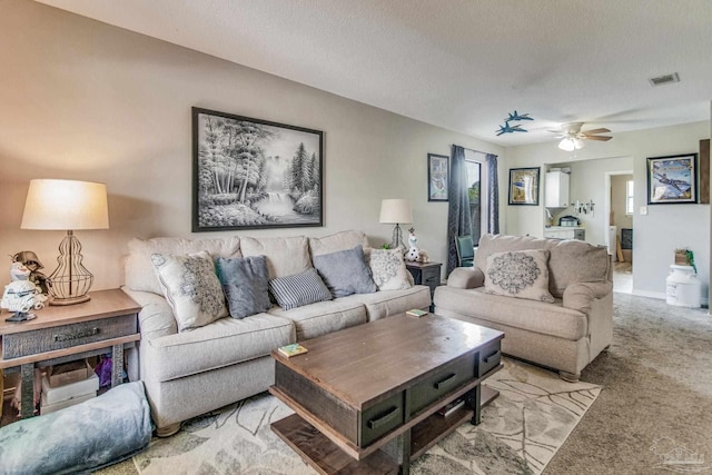 living room with light carpet, a textured ceiling, and ceiling fan