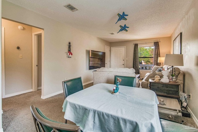 carpeted dining room featuring a textured ceiling