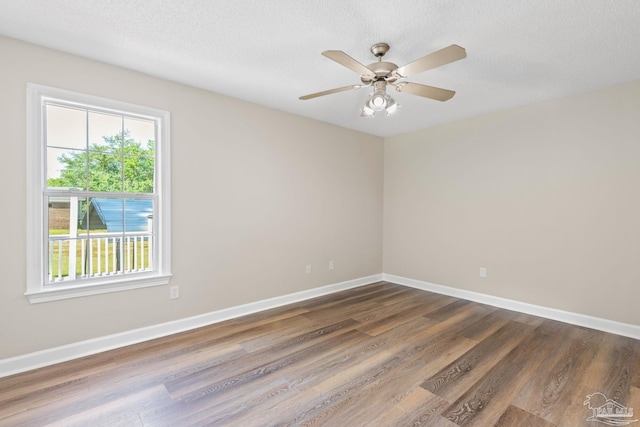 spare room with a textured ceiling, ceiling fan, and dark wood-type flooring