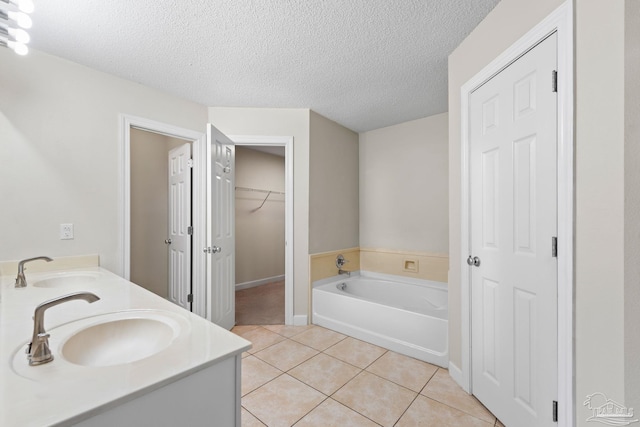 bathroom featuring tile patterned flooring, vanity, a textured ceiling, and a bathtub