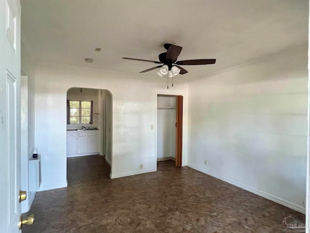 empty room with crown molding, ceiling fan, and dark tile patterned flooring