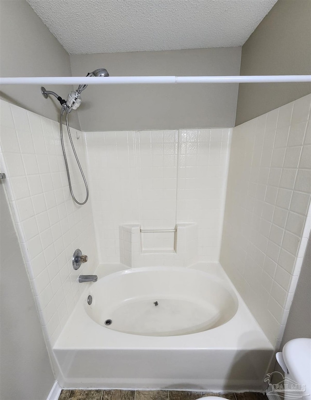 bathroom featuring a textured ceiling, toilet, and bathing tub / shower combination