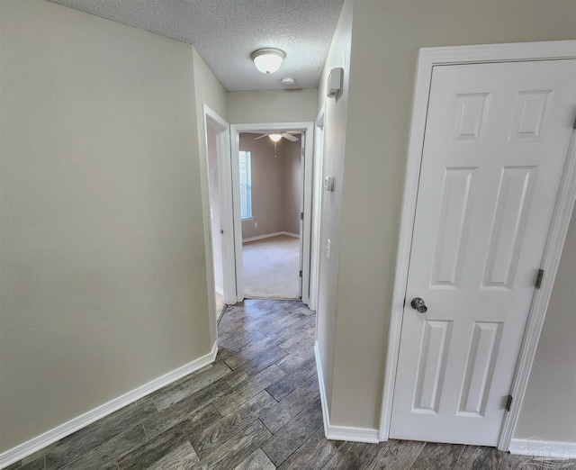 hallway with wood tiled floor, a textured ceiling, and baseboards