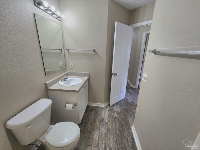 half bath featuring baseboards, vanity, toilet, and wood tiled floor