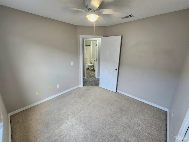 carpeted spare room with a ceiling fan, visible vents, and baseboards