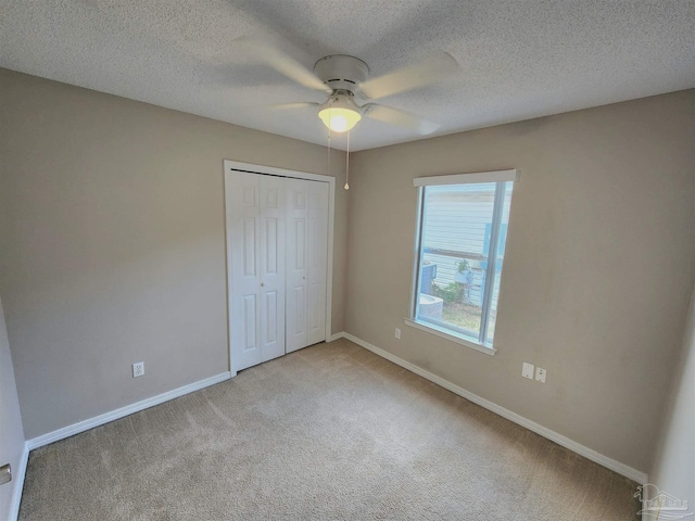 unfurnished bedroom featuring carpet, a textured ceiling, baseboards, and a closet