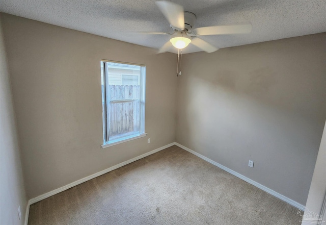 carpeted spare room with a ceiling fan, baseboards, and a textured ceiling