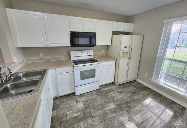 kitchen with white appliances, white cabinets, and a sink