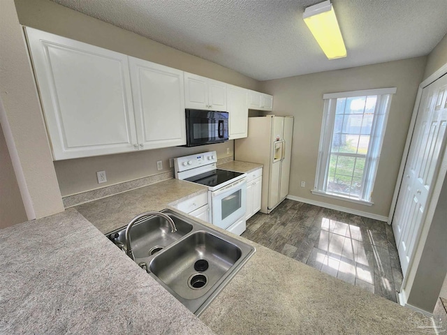 kitchen with dark wood finished floors, white cabinets, a sink, a textured ceiling, and white appliances