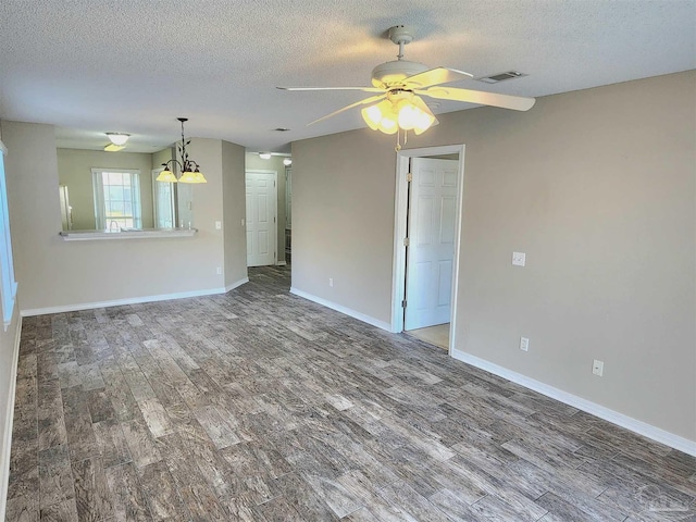 empty room featuring visible vents, a textured ceiling, baseboards, and wood finished floors