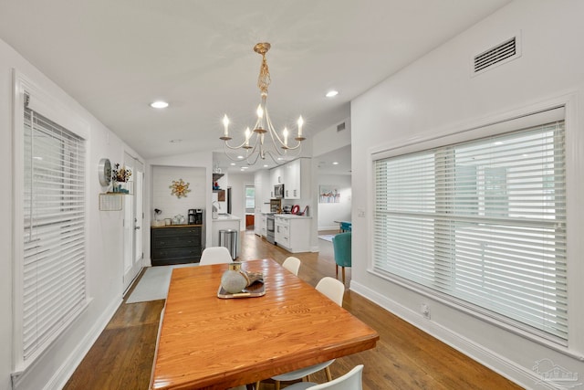 dining room featuring an inviting chandelier, vaulted ceiling, and light wood-type flooring