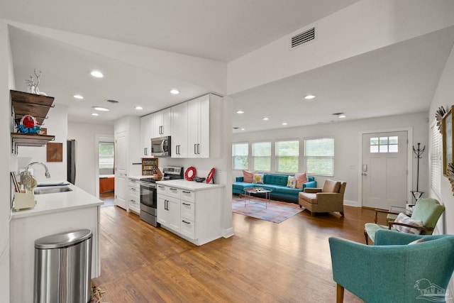 kitchen featuring white cabinets, wood-type flooring, sink, and appliances with stainless steel finishes