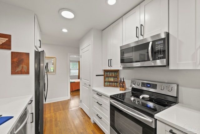 kitchen with white cabinets, light wood-type flooring, and stainless steel appliances