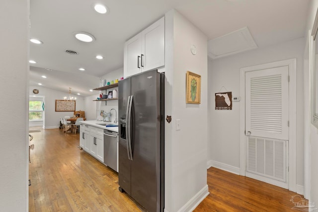 kitchen featuring appliances with stainless steel finishes, light hardwood / wood-style flooring, and white cabinetry