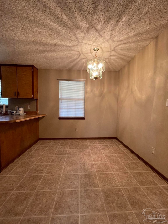 unfurnished dining area with a notable chandelier and a textured ceiling